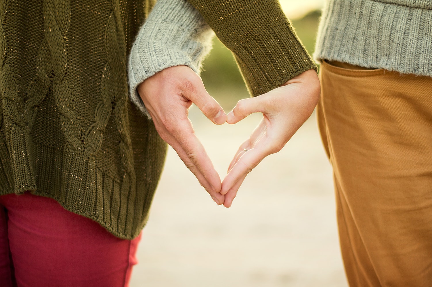 couple forming heart shape with their hands