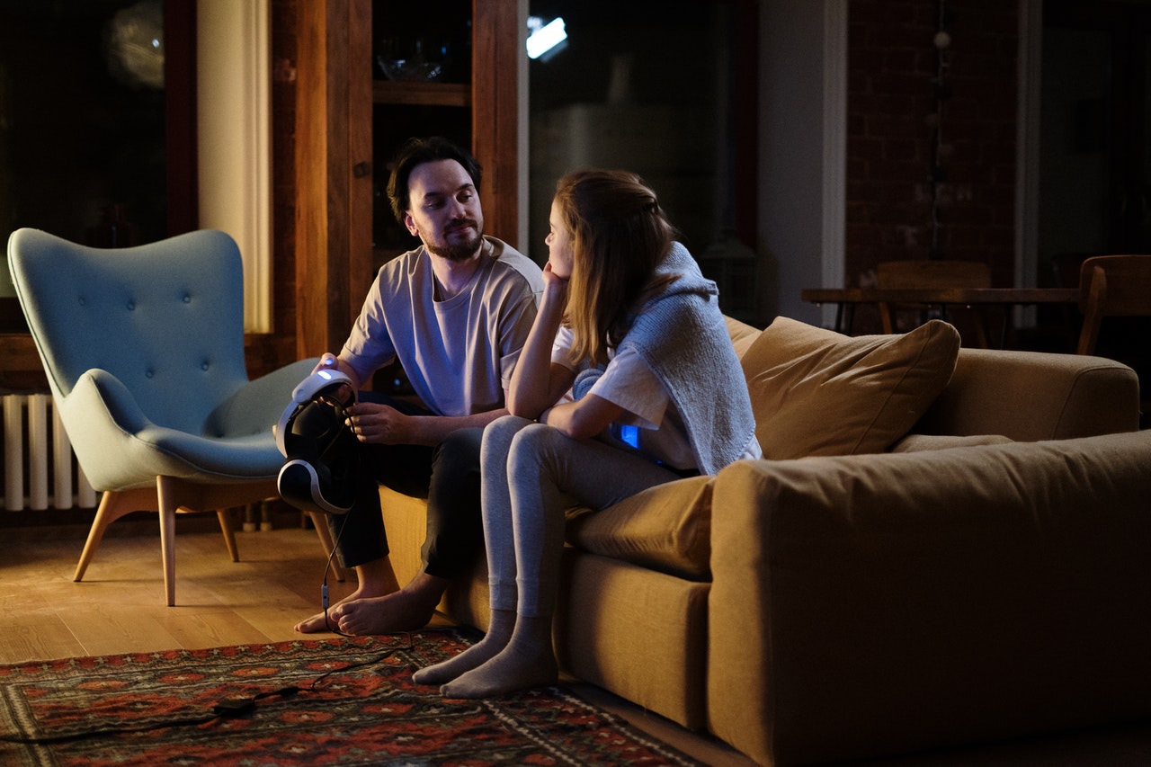 A couple sitting on a couch affectionately looking at each other