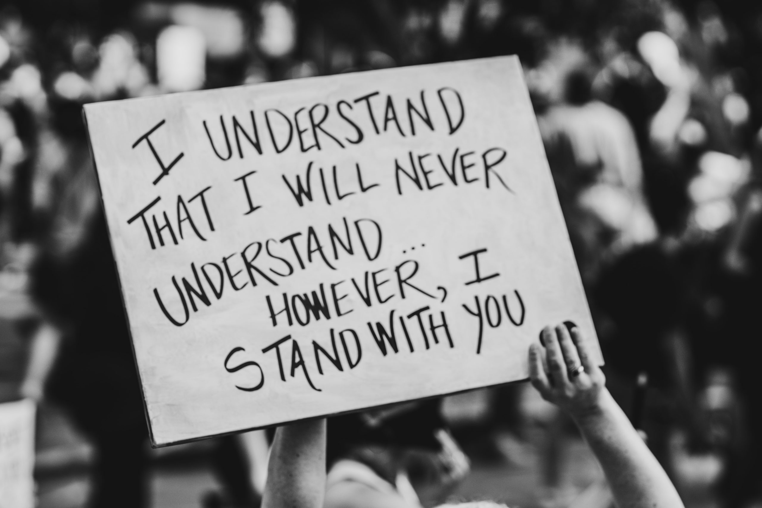 A protest placard reads "I understand that I will never understand, however, I stand with you