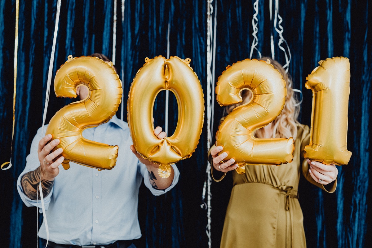 A couple holding 2021 gold balloons