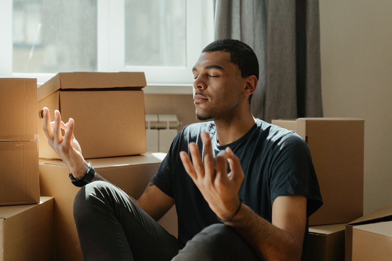 A male meditating in the middle of cardboard boxes