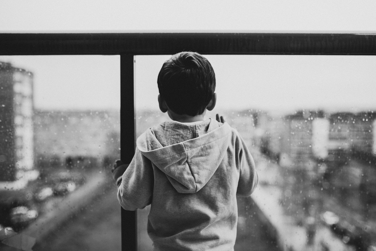 A black and white photo of a small boy looking at the city