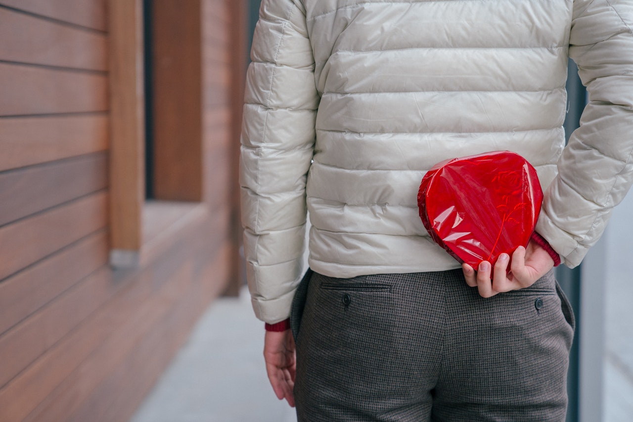 A man holding a Valentine's gift at his back