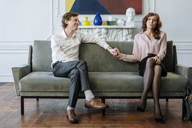 A couple sitting on a couch, holding hands