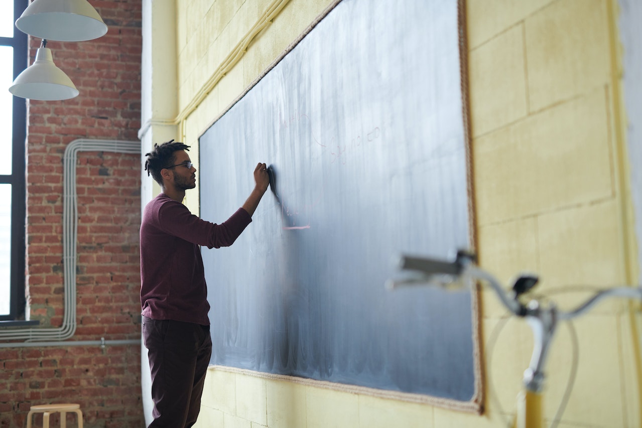 A mid-thirties school teacher, writing on the black board