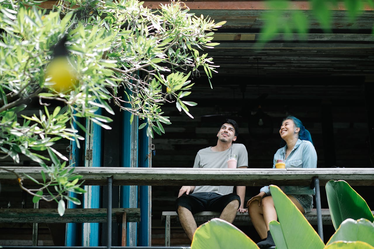 A young man and woman chatting over cold drinks at an outdoor setting.
