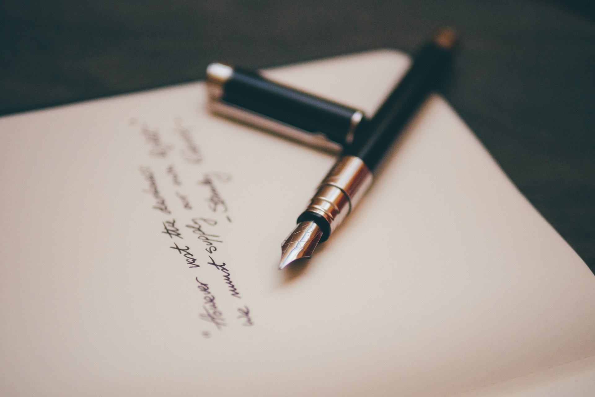A classic fountain pen resting on paper with an inspiring handwritten quote.