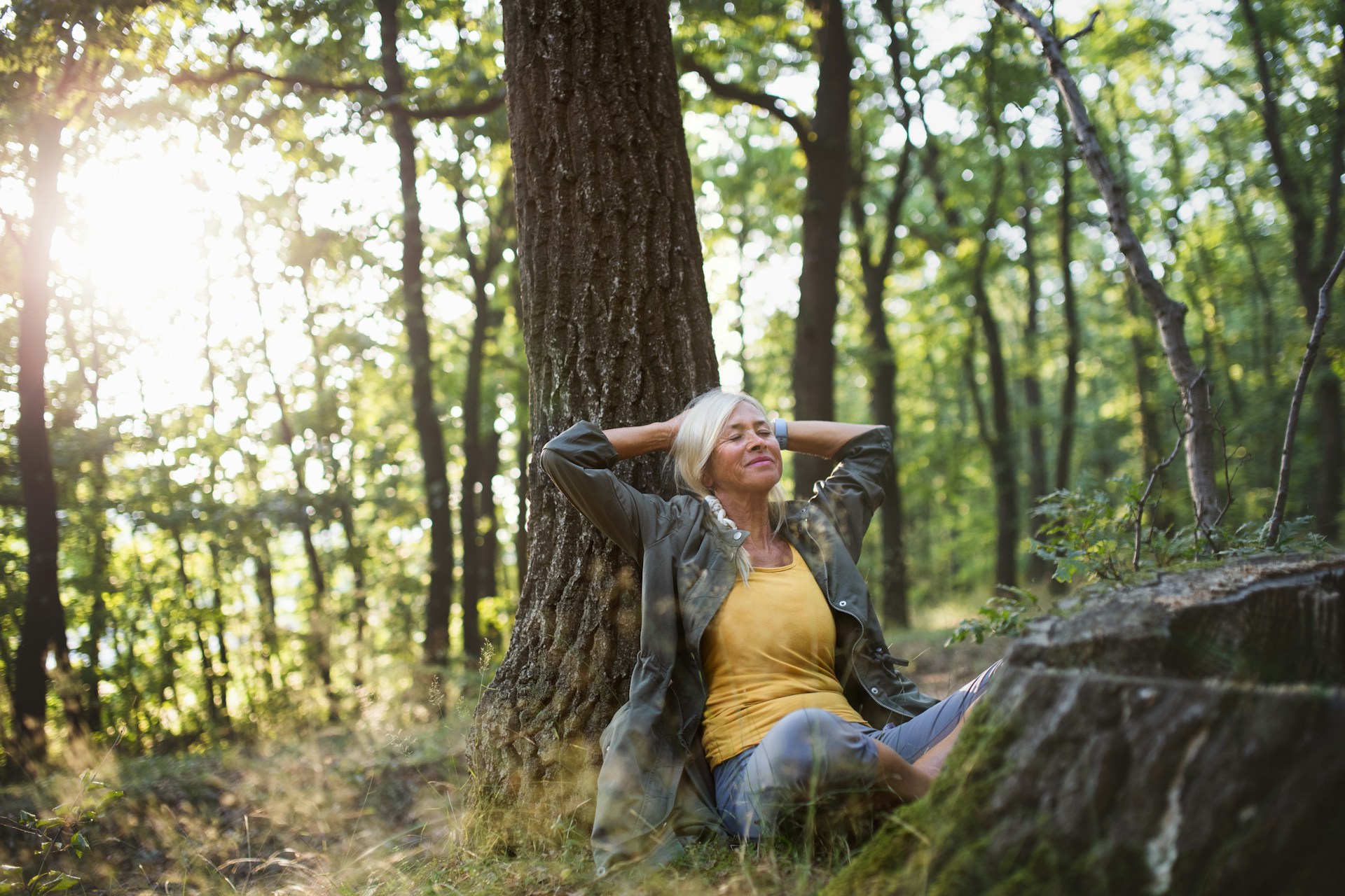 A woman sitting under the tree positively visualizing life